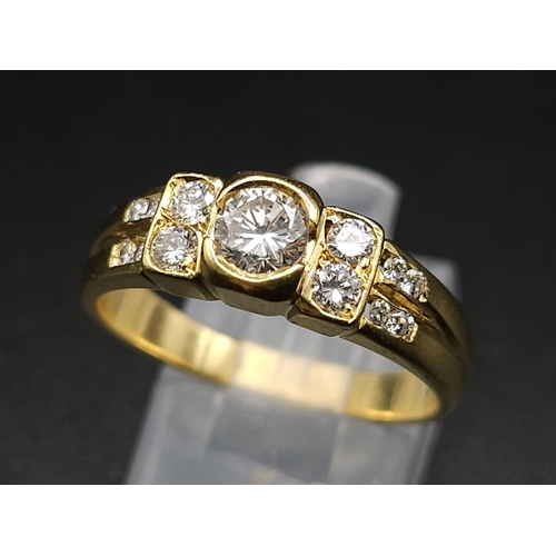 618 - An 18K Yellow Gold and Diamond Ring. A High grade central bright round cut diamond with 12 further d... 