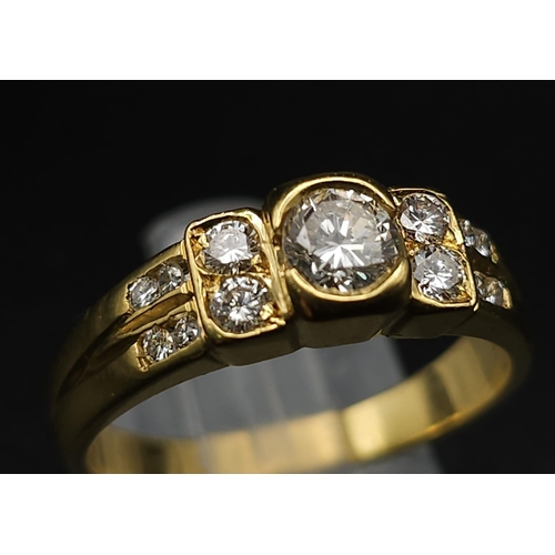 618 - An 18K Yellow Gold and Diamond Ring. A High grade central bright round cut diamond with 12 further d... 