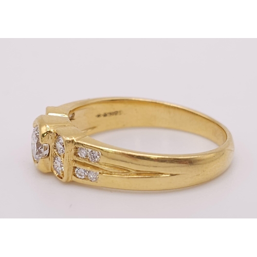 618 - An 18K Yellow Gold and Diamond Ring. A High grade central bright round cut diamond with 12 further d... 