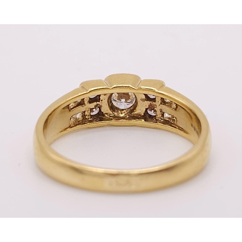 618 - An 18K Yellow Gold and Diamond Ring. A High grade central bright round cut diamond with 12 further d... 