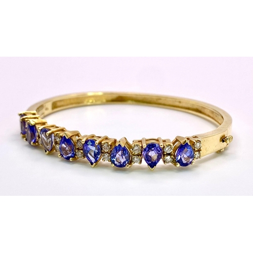 383 - An Alluring 14K Yellow Gold, Amethyst and Diamond Bangle. 
High-grade, clean pear-cut amethysts sepa... 