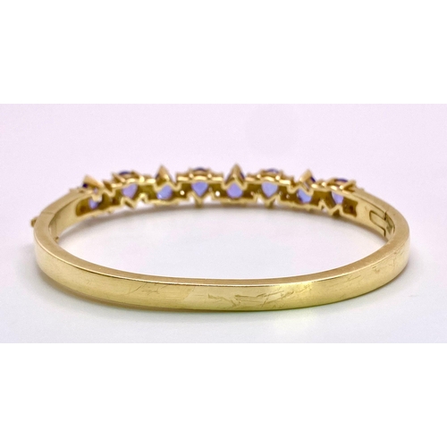 383 - An Alluring 14K Yellow Gold, Amethyst and Diamond Bangle. 
High-grade, clean pear-cut amethysts sepa... 