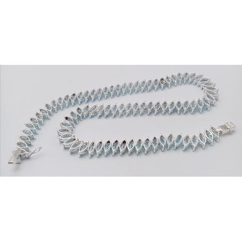 700B - A icy Marquise Cut Blue Topaz, Tennis Necklace set in 925 Silver. Weighing 68.65g in total, this gor... 