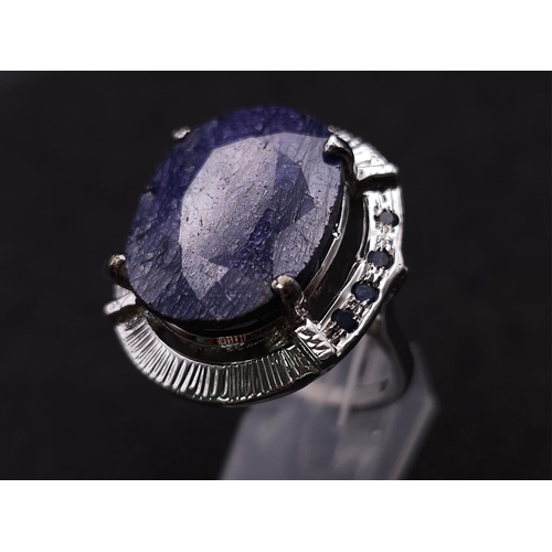 655B - A Blue Sapphire and 925 Silver Ring. Oval cut central sapphire with small sapphire accents. Size R. ... 