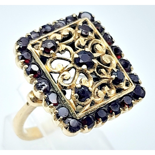 766B - A showstopper, 18KT Yellow Gold, Garnet Set Ring.
A stunningly unique, gold & stone interlacing desi... 