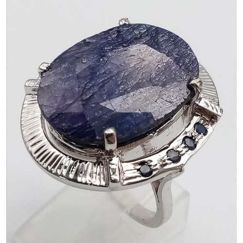 655B - A Blue Sapphire and 925 Silver Ring. Oval cut central sapphire with small sapphire accents. Size R. ... 