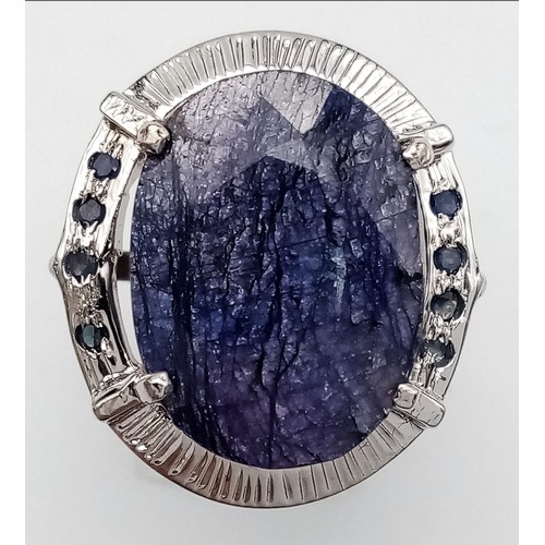 655B - A Blue Sapphire and 925 Silver Ring. Oval cut central sapphire with small sapphire accents. Size R. ... 