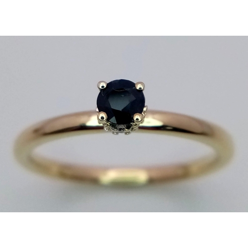 377 - A 9 K yellow gold ring with a single sapphire, standing proud, with a halo of diamonds on its base. ... 