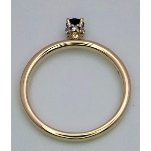 377 - A 9 K yellow gold ring with a single sapphire, standing proud, with a halo of diamonds on its base. ... 