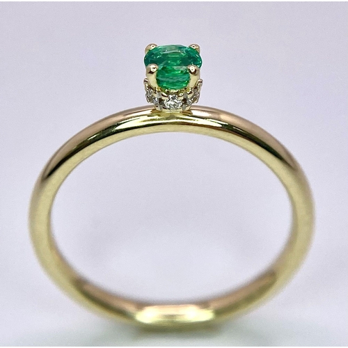 370 - A 9 K yellow gold ring with a single round cut quality emerald standing proud and a halo of diamonds... 