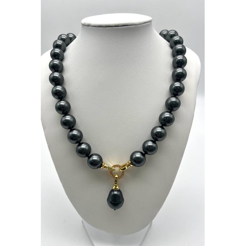 659 - A Metallic Grey South Sea Pearl Shell Bead Necklace with Teardrop Pendant. Gilded and white stone sn... 