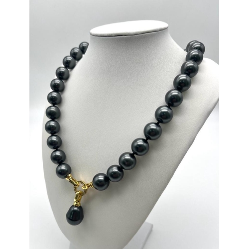 659 - A Metallic Grey South Sea Pearl Shell Bead Necklace with Teardrop Pendant. Gilded and white stone sn... 