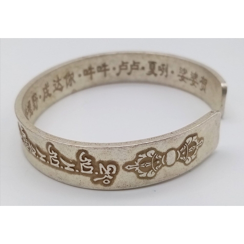 297 - A Tibetan silver bangle with Tibetan language characters on the outside and Chinese language charact... 