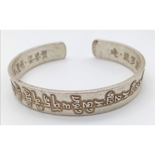 297 - A Tibetan silver bangle with Tibetan language characters on the outside and Chinese language charact... 