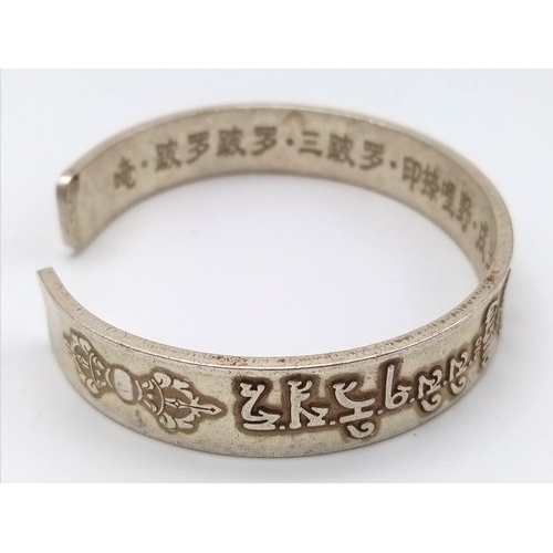 297 - A Tibetan silver bangle with Tibetan language characters on the outside and Chinese language charact... 