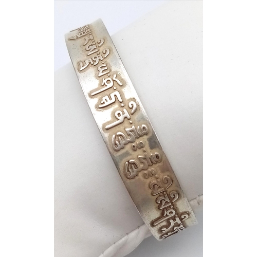 297 - A Tibetan silver bangle with Tibetan language characters on the outside and Chinese language charact... 