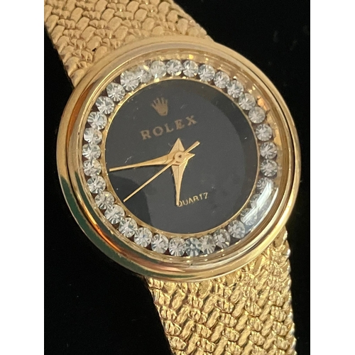 315 - Ladies Quartz WRISTWATCH in Gold Tone. Black face model with jewelled surround. Full working order.