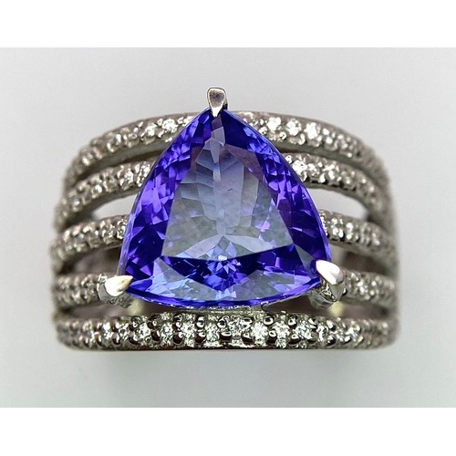 80 - An 18K White Gold, Tanzanite and Diamond Ring. Trillion cut tanzanite with a five row diamond arch f... 