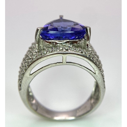 80 - An 18K White Gold, Tanzanite and Diamond Ring. Trillion cut tanzanite with a five row diamond arch f... 