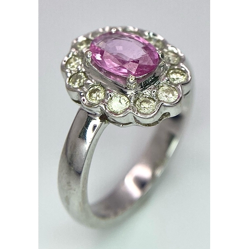 87 - A 9K White Gold, Diamond and Pink Sapphire Ring. Central oval cut pink sapphire with a diamond halo.... 