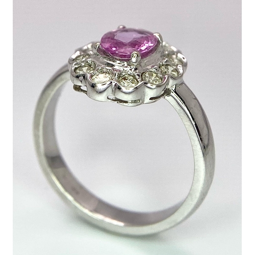 87 - A 9K White Gold, Diamond and Pink Sapphire Ring. Central oval cut pink sapphire with a diamond halo.... 