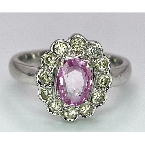 87 - A 9K White Gold, Diamond and Pink Sapphire Ring. Central oval cut pink sapphire with a diamond halo.... 