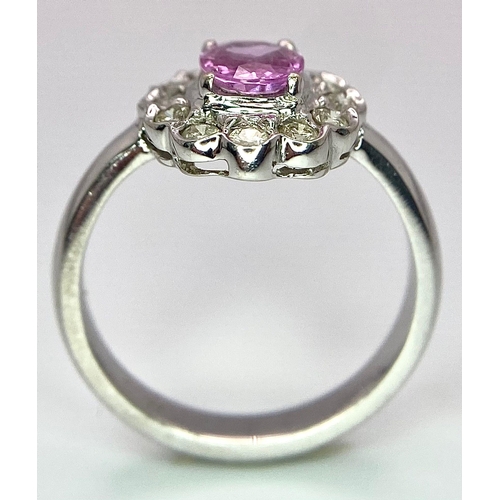 87 - A 9K White Gold, Diamond and Pink Sapphire Ring. Central oval cut pink sapphire with a diamond halo.... 