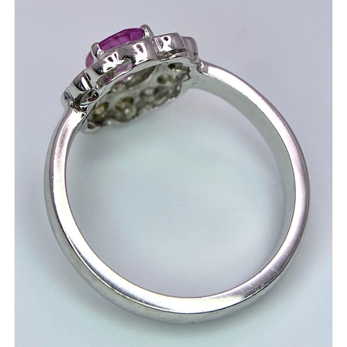 87 - A 9K White Gold, Diamond and Pink Sapphire Ring. Central oval cut pink sapphire with a diamond halo.... 