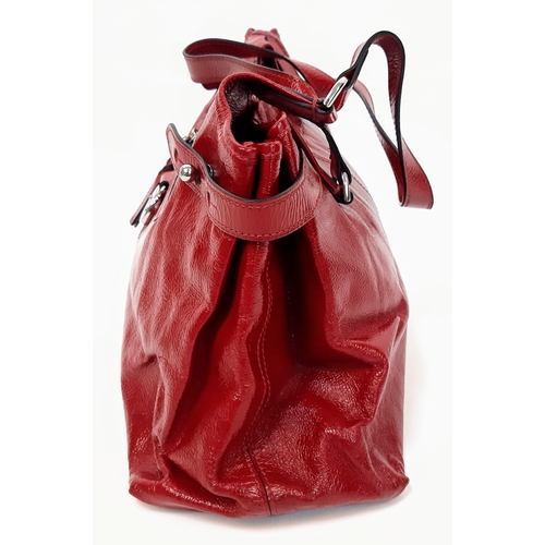 156 - A Mulberry Patent Red Leather Handbag. Textured exterior with a central zipped pocket. Silver-tone h... 