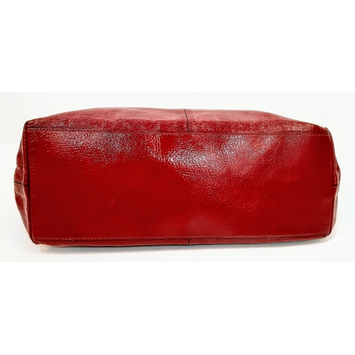 156 - A Mulberry Patent Red Leather Handbag. Textured exterior with a central zipped pocket. Silver-tone h... 