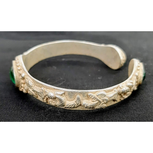 196 - A vintage Chinese silver bangle with green Peking Glass cabochons and eight old sage men adorning th... 