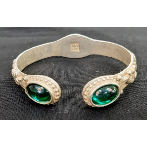 196 - A vintage Chinese silver bangle with green Peking Glass cabochons and eight old sage men adorning th... 