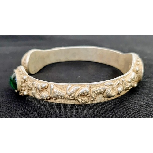 196 - A vintage Chinese silver bangle with green Peking Glass cabochons and eight old sage men adorning th... 