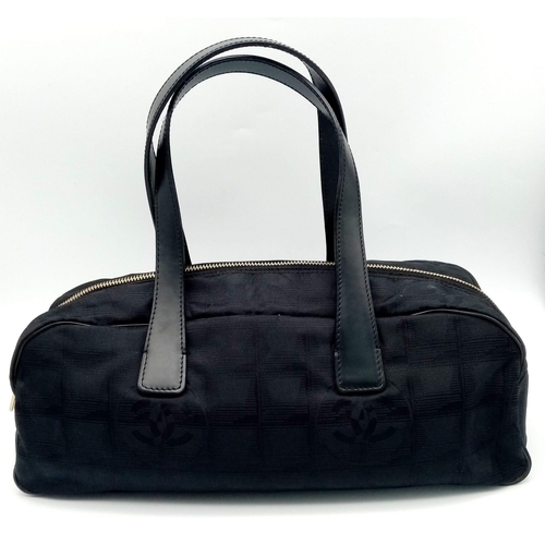 348 - A Chanel Black Travel Line Bag. Canvas exterior with leather straps, four protective base studs and ... 