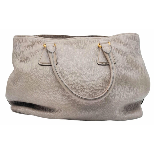 510 - A Prada Vitello Daino Tote Pomice Bag. Textured leather exterior with gold-tone hardware. Decorative... 