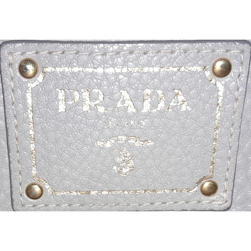 510 - A Prada Vitello Daino Tote Pomice Bag. Textured leather exterior with gold-tone hardware. Decorative... 