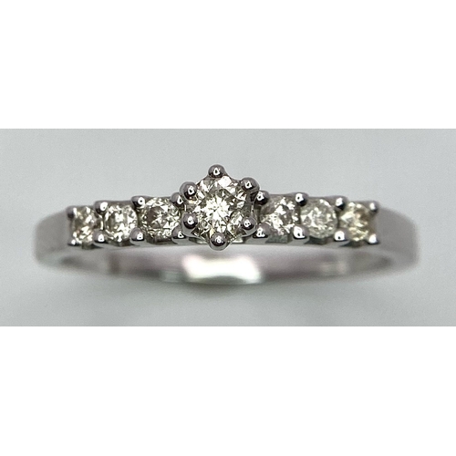 1442 - A 9K White Gold Diamond Ring. A tinted central cut round diamond with diamond accents on shoulders. ... 