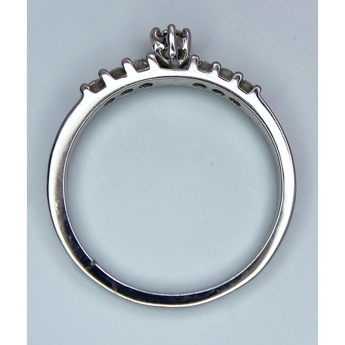 1442 - A 9K White Gold Diamond Ring. A tinted central cut round diamond with diamond accents on shoulders. ... 