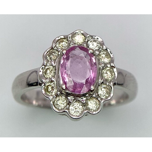 790 - A 9K White Gold, Diamond and Pink Sapphire Ring. Central oval cut pink sapphire with a diamond halo.... 