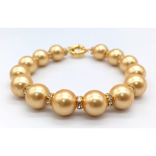 866 - A South Sea Pearl Shell Gold Tone Bead Bracelet. White stone spacers. Gilded clasp. 18cm