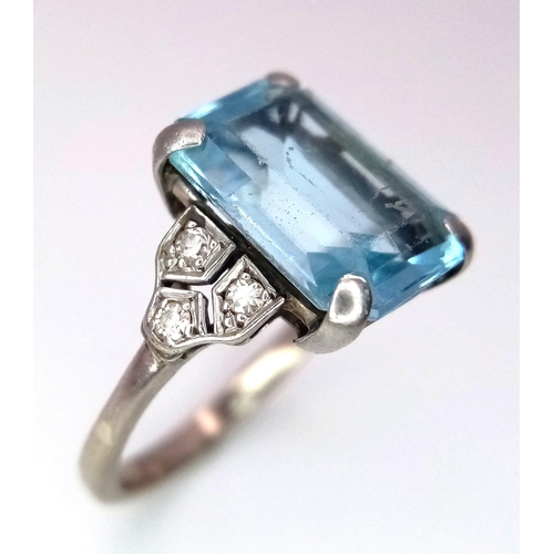 285 - A 9 K white gold ring with an emerald cut aquamarine and a trilogy of diamonds on each shoulder. Rin... 