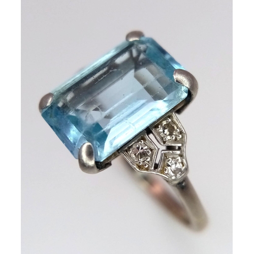 285 - A 9 K white gold ring with an emerald cut aquamarine and a trilogy of diamonds on each shoulder. Rin... 