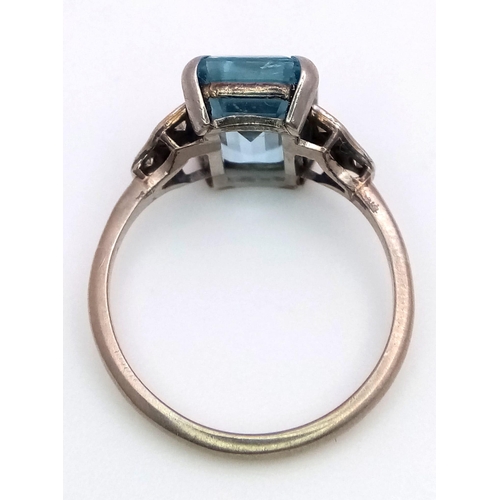 285 - A 9 K white gold ring with an emerald cut aquamarine and a trilogy of diamonds on each shoulder. Rin... 