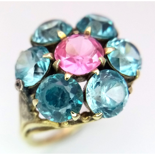 395 - A 9K YELLOW GOLD, BLUE AND PINK STONE CLUSTER RING. 4.2G. SIZE I