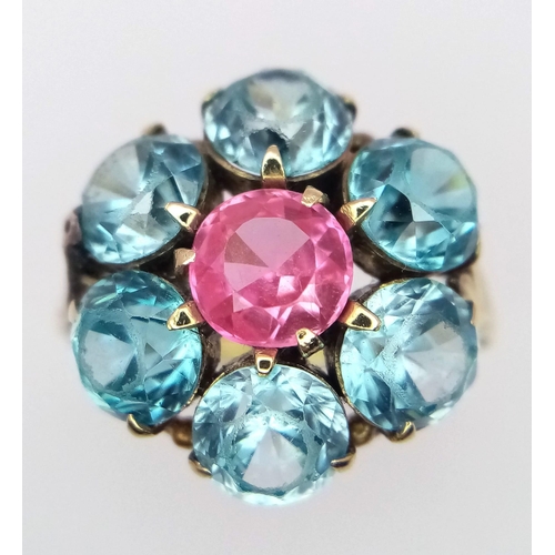 395 - A 9K YELLOW GOLD, BLUE AND PINK STONE CLUSTER RING. 4.2G. SIZE I