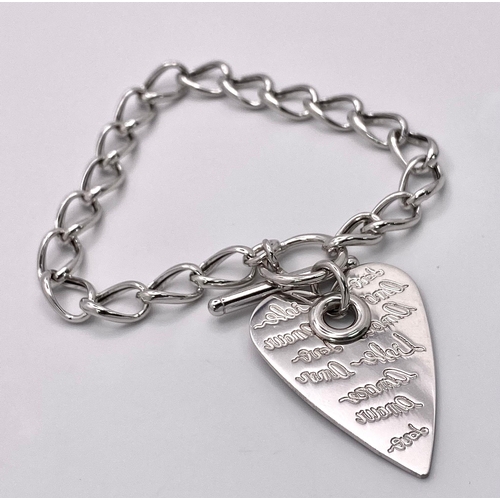 1242 - A sterling silver bracelet with a T bar toggle and a large heart shaped charm with the word LOVE in ... 