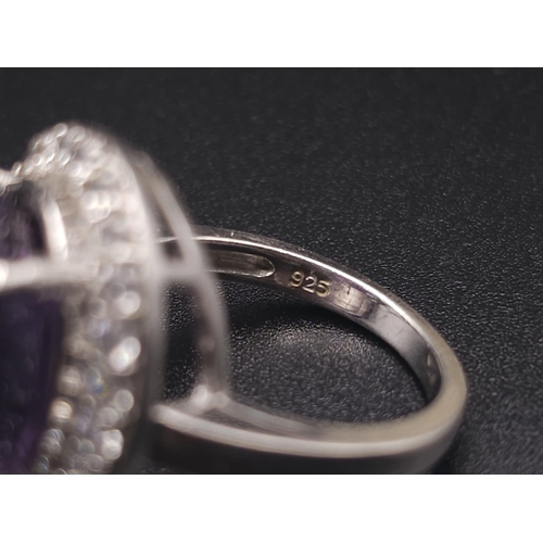 1103 - A STUNNING SILVER RING WITH LARGE AMETHYST SURROUNDED BY SPARKLING ZIRCONIA STONES .  6.1gms   size ... 