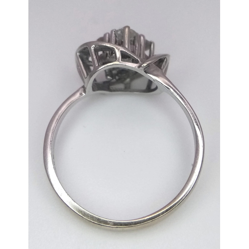 1003 - An 18K White Gold Four Stone Diamond Ring. Four brilliant round cut diamonds in a swirl setting. 1ct... 