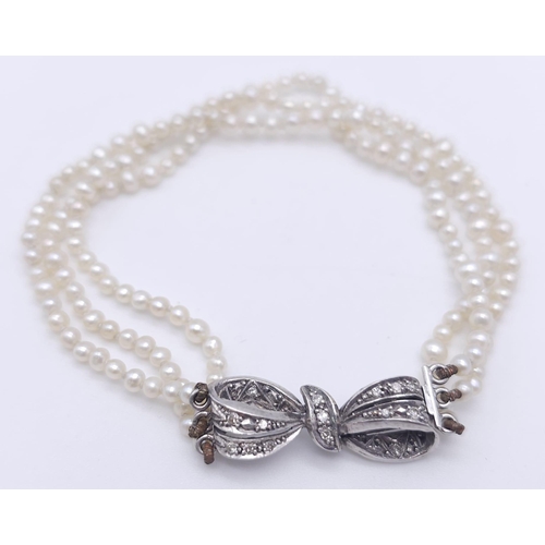 376 - A Triple Strand Fresh Pearl Bracelet with a 18kt White Gold, Diamond Set Bow Clasp.
Measuring 12cm i... 