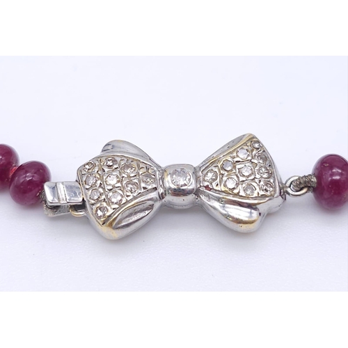 1077 - A superb graduating Ruby Red Stone Beaded Necklace with a 18kt White Gold, Diamond Set Bow Clasp. Me... 